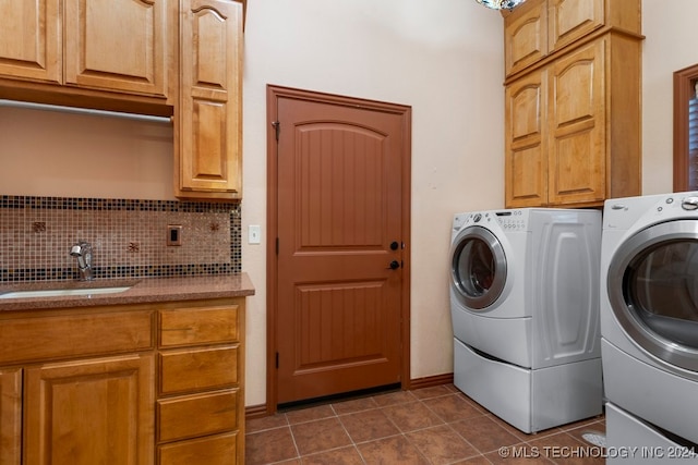 laundry room featuring separate washer and dryer, sink, dark tile patterned floors, and cabinets