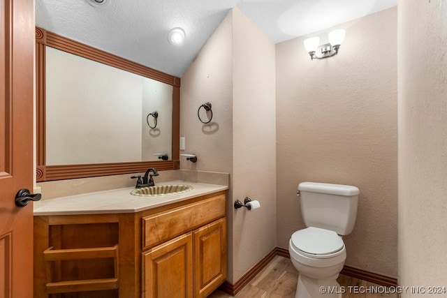 bathroom featuring vanity, lofted ceiling, wood-type flooring, a textured ceiling, and toilet