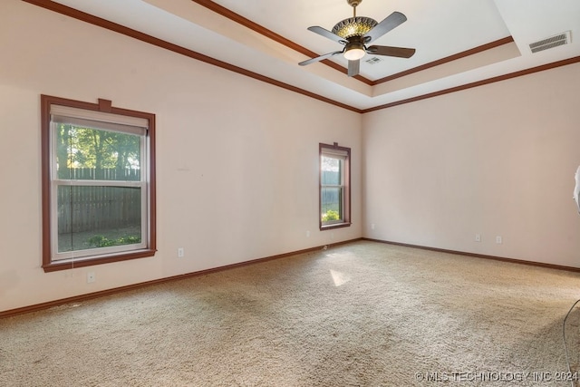 unfurnished room with a raised ceiling, carpet flooring, ceiling fan, and a wealth of natural light