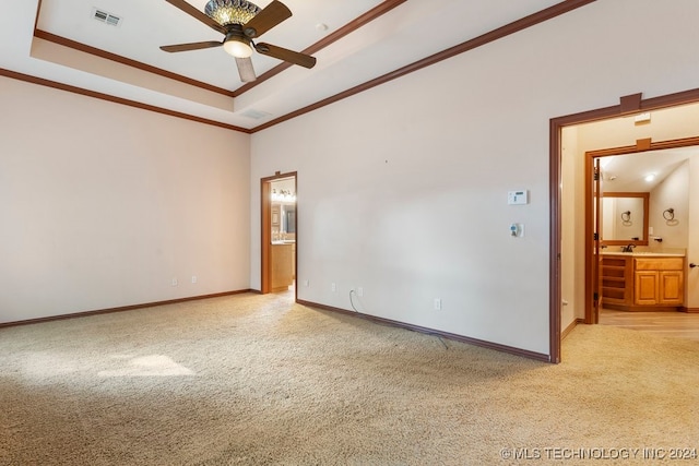 carpeted empty room featuring a tray ceiling, ceiling fan, and crown molding