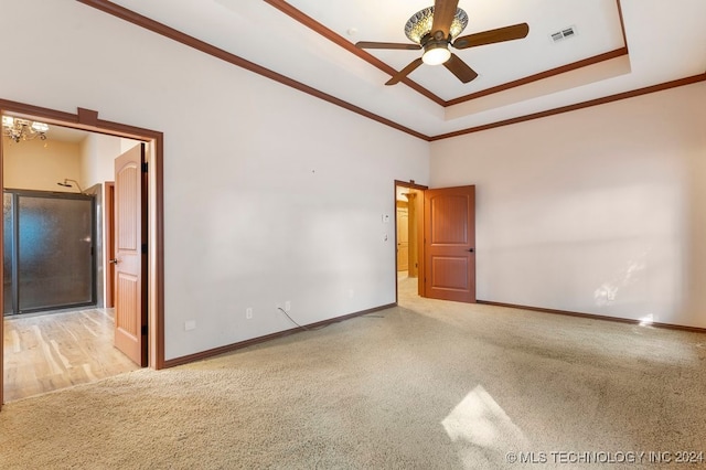 unfurnished room featuring a raised ceiling, ceiling fan, light colored carpet, and ornamental molding