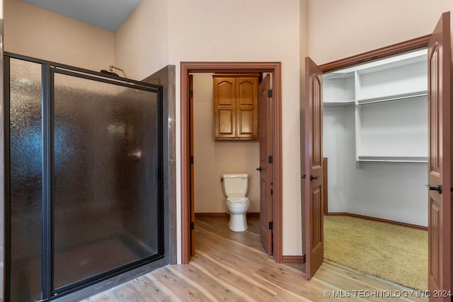 bathroom featuring walk in shower, hardwood / wood-style floors, and toilet