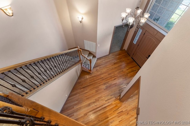 foyer featuring a notable chandelier, light wood-type flooring, and a high ceiling