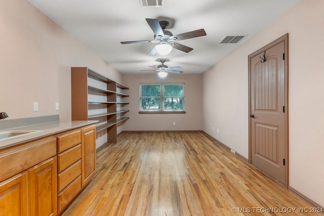 interior space with light hardwood / wood-style flooring, built in desk, ceiling fan, and sink