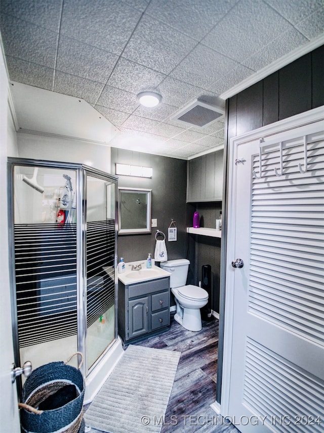 bathroom with toilet, wood-type flooring, a paneled ceiling, an enclosed shower, and vanity