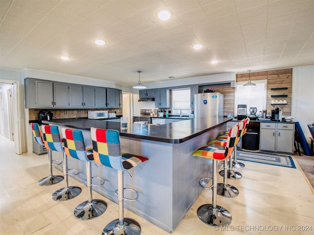 7386 Sooner Rd, Kingston, OK 73439 - kitchen featuring stainless steel appliances, dark countertops, a kitchen breakfast bar, hanging light fixtures, and a sink