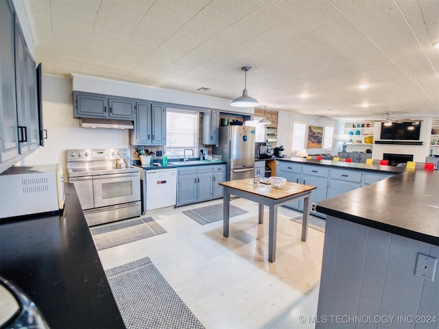 7386 Sooner Rd, Kingston, OK 73439 - kitchen with appliances with stainless steel finishes, dark countertops, under cabinet range hood, a sink, and ceiling fan