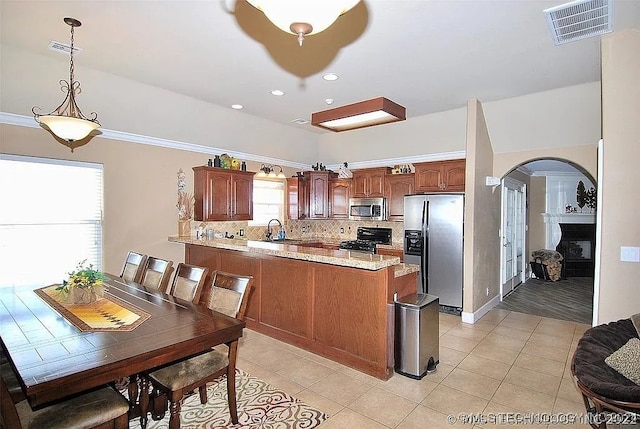 kitchen with tasteful backsplash, kitchen peninsula, stainless steel appliances, decorative light fixtures, and sink