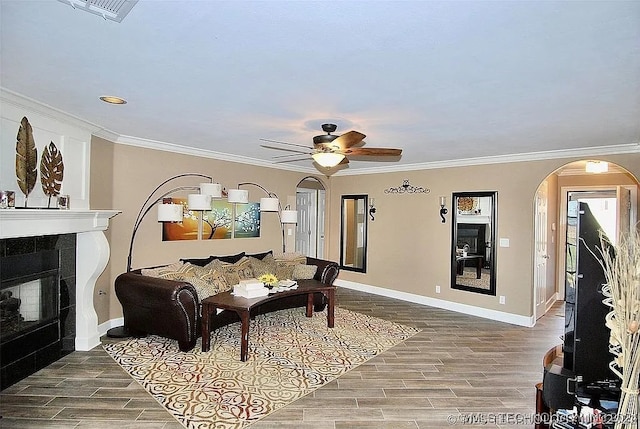 living room with a fireplace, ornamental molding, ceiling fan, and hardwood / wood-style flooring