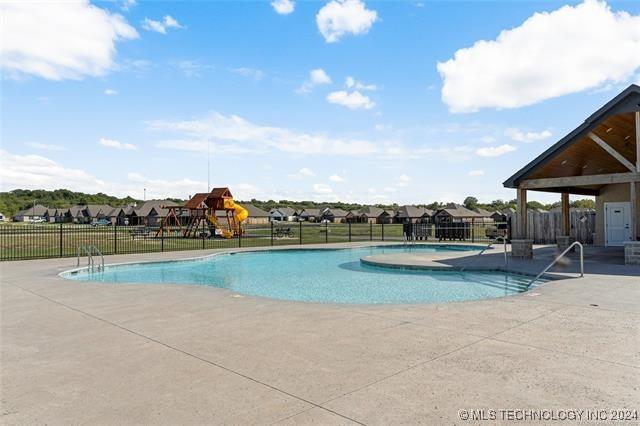 view of pool with a playground and a patio