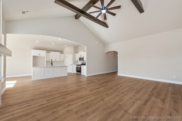 unfurnished living room featuring beam ceiling, high vaulted ceiling, hardwood / wood-style floors, and ceiling fan