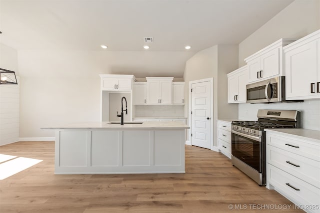 kitchen featuring appliances with stainless steel finishes, a kitchen island with sink, sink, and white cabinets