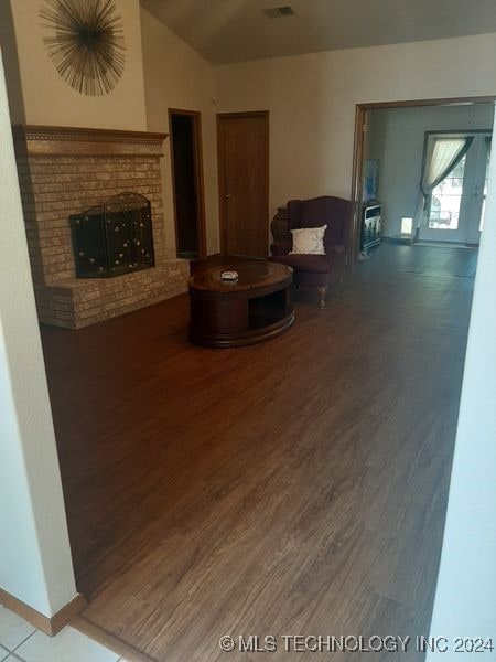 living room featuring a brick fireplace, lofted ceiling, and hardwood / wood-style floors