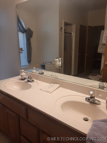 bathroom featuring a shower with shower door and vanity