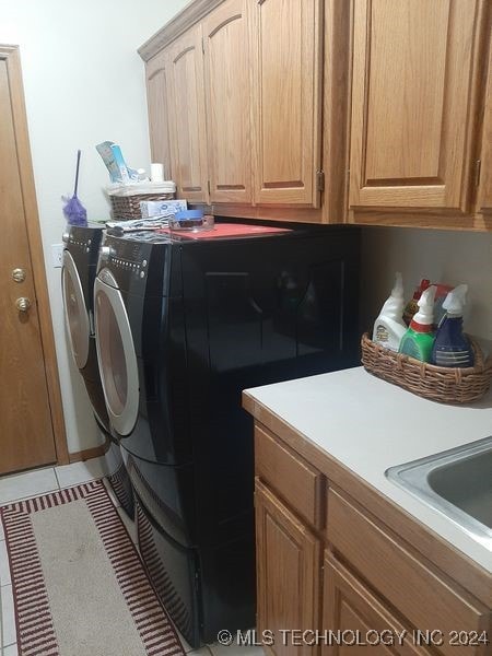 washroom featuring washer and clothes dryer, cabinets, and light tile patterned flooring