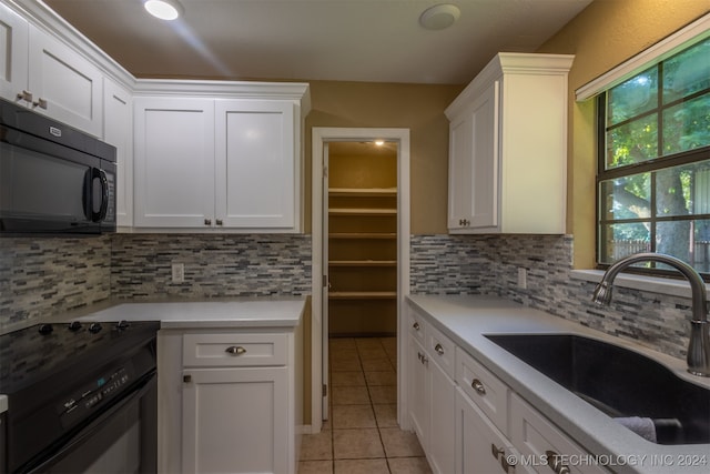 kitchen with black appliances, tasteful backsplash, sink, and white cabinets