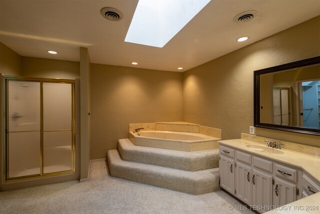 bathroom featuring shower with separate bathtub, a skylight, and vanity