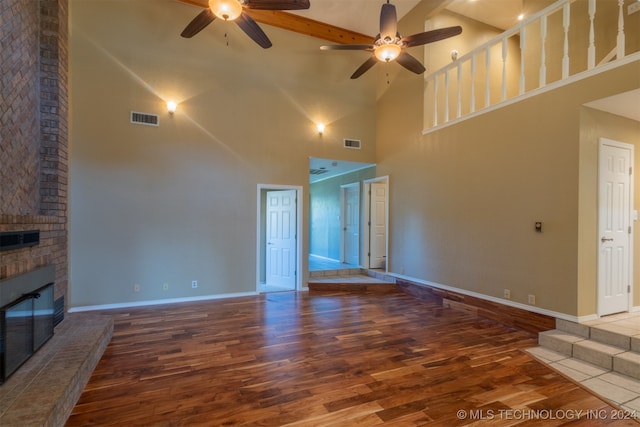 unfurnished living room featuring wood-type flooring, a brick fireplace, high vaulted ceiling, and ceiling fan