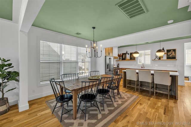 dining space featuring sink, light hardwood / wood-style flooring, and a chandelier