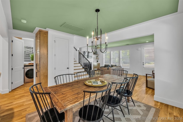 dining space featuring washer / clothes dryer, an inviting chandelier, and light hardwood / wood-style flooring