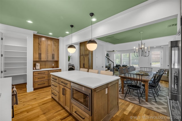 kitchen featuring light hardwood / wood-style floors, hanging light fixtures, and stainless steel microwave