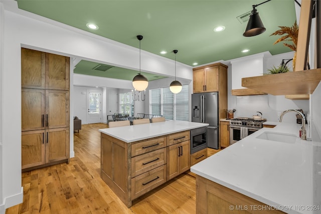 kitchen featuring light hardwood / wood-style floors, sink, hanging light fixtures, a kitchen island, and high quality appliances