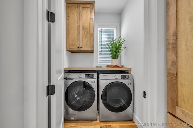 washroom featuring light wood-type flooring, washing machine and clothes dryer, and cabinets