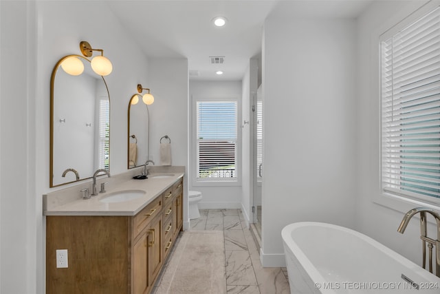 bathroom with a healthy amount of sunlight, a washtub, and toilet