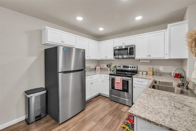 kitchen featuring sink, white cabinetry, light hardwood / wood-style flooring, stainless steel appliances, and light stone countertops