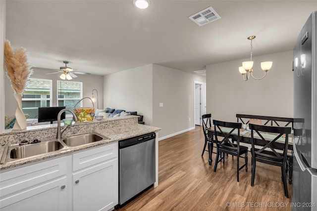 kitchen with appliances with stainless steel finishes, light hardwood / wood-style floors, white cabinets, decorative light fixtures, and sink