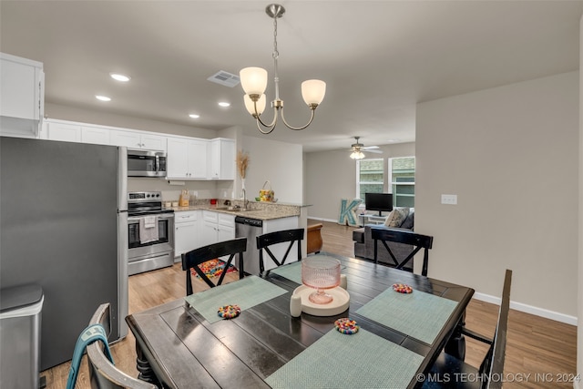 dining room featuring light hardwood / wood-style flooring, ceiling fan with notable chandelier, and sink