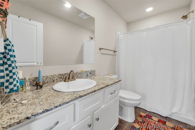 bathroom with a shower with shower curtain, hardwood / wood-style floors, vanity, and toilet