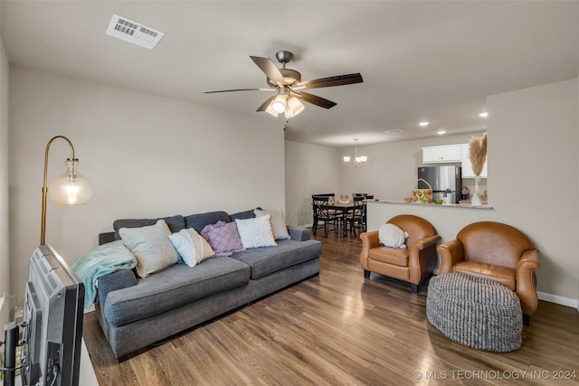 living room with heating unit, ceiling fan with notable chandelier, and dark wood-type flooring