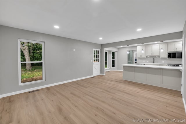 kitchen with white cabinets, sink, kitchen peninsula, tasteful backsplash, and light hardwood / wood-style flooring