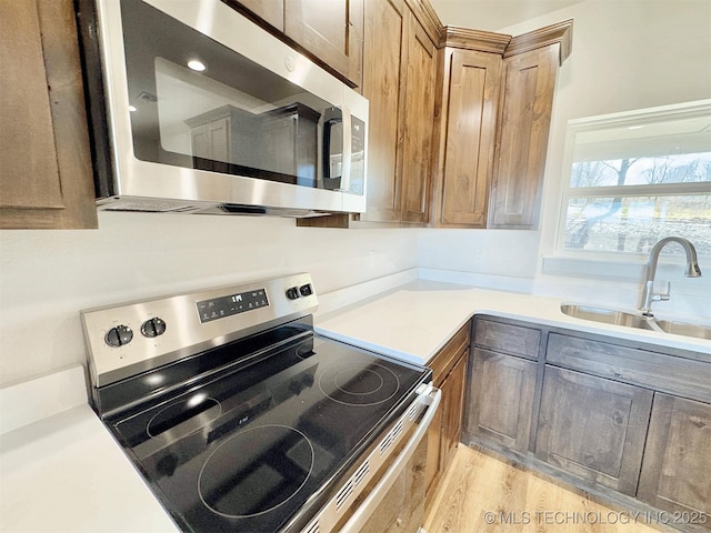 kitchen featuring stainless steel appliances, sink, and light hardwood / wood-style flooring