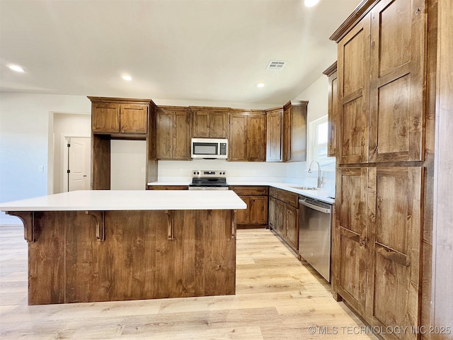 kitchen featuring sink, a breakfast bar area, stainless steel appliances, a center island, and light hardwood / wood-style floors