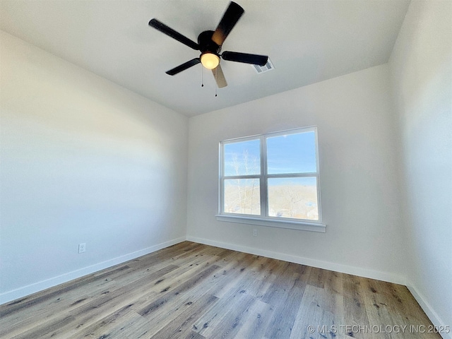 spare room featuring visible vents, ceiling fan, baseboards, and wood finished floors