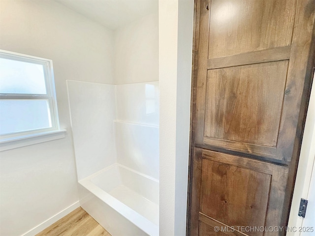 bathroom with a shower, wood finished floors, and baseboards