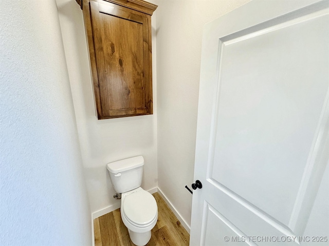 bathroom with wood finished floors, toilet, and baseboards