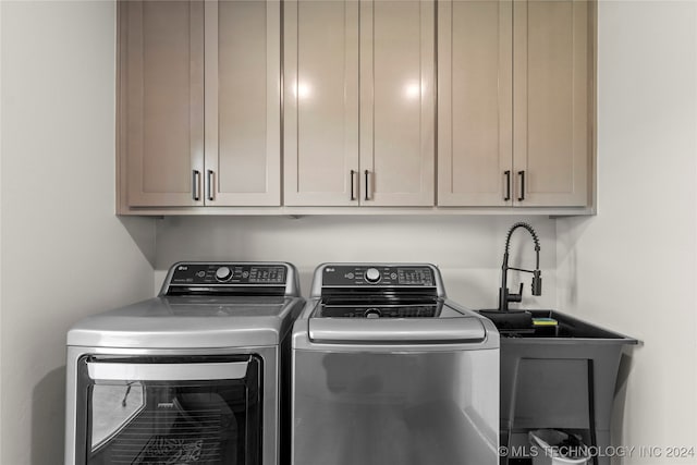 washroom with washing machine and clothes dryer and cabinets