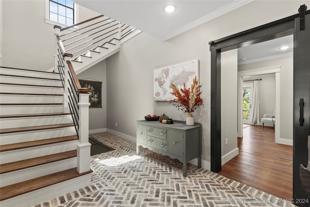 interior space featuring wood-type flooring, crown molding, and a barn door