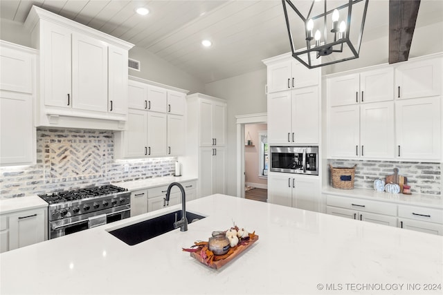 kitchen with appliances with stainless steel finishes, white cabinetry, sink, and pendant lighting