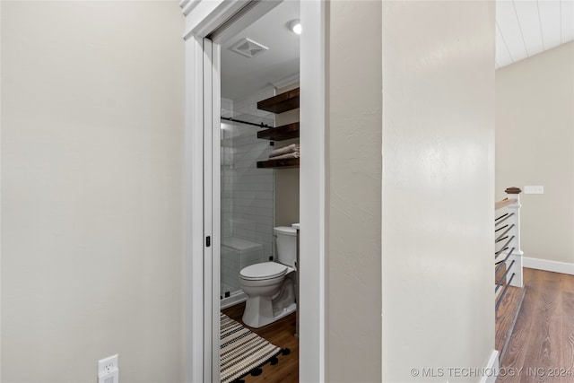 bathroom featuring hardwood / wood-style flooring, a shower with door, and toilet