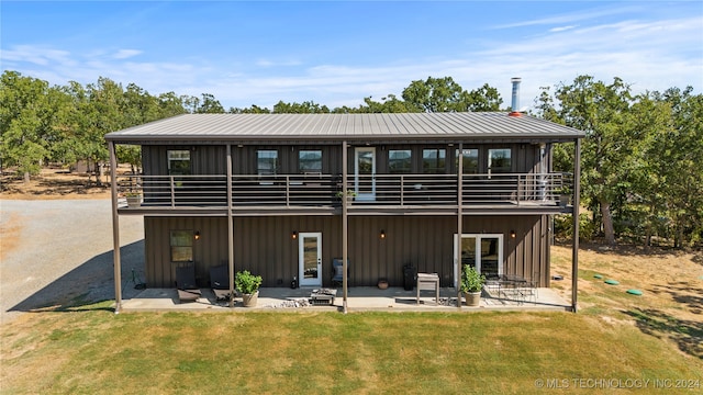 rear view of house with a patio, a balcony, and a yard