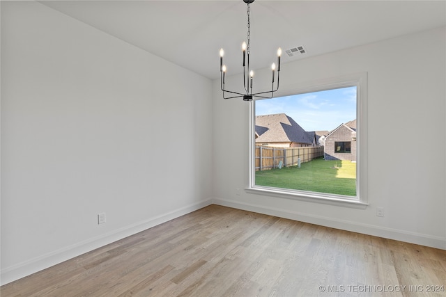 unfurnished dining area with an inviting chandelier and light wood-type flooring