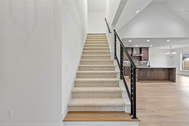 stairway featuring a chandelier, sink, high vaulted ceiling, and wood-type flooring