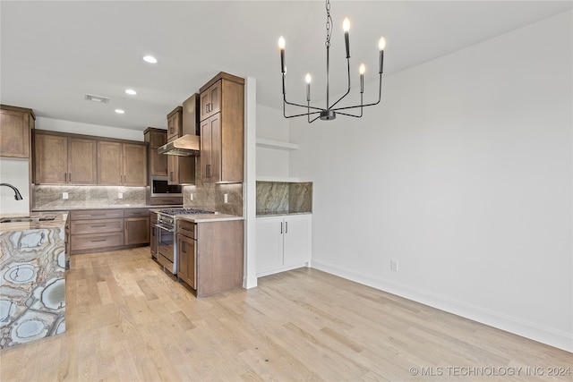 kitchen featuring decorative backsplash, light wood-type flooring, high end stainless steel range, and wall chimney exhaust hood