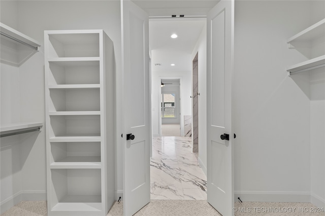 walk in closet with ceiling fan and light colored carpet