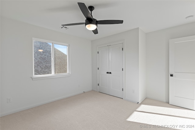 unfurnished bedroom featuring ceiling fan, a closet, and light carpet