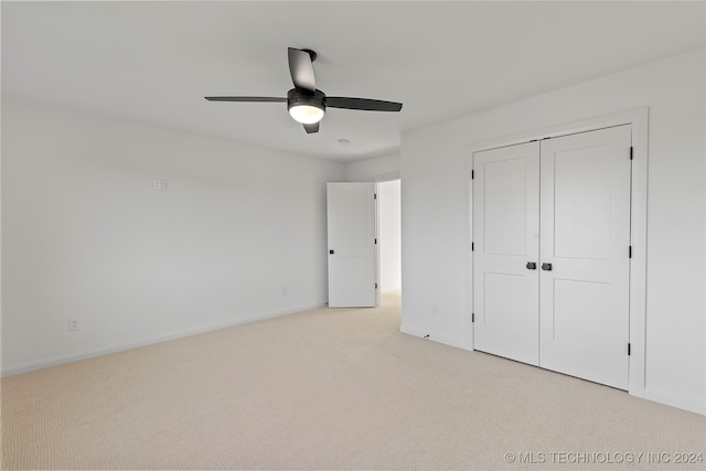 unfurnished bedroom featuring ceiling fan, a closet, and light carpet